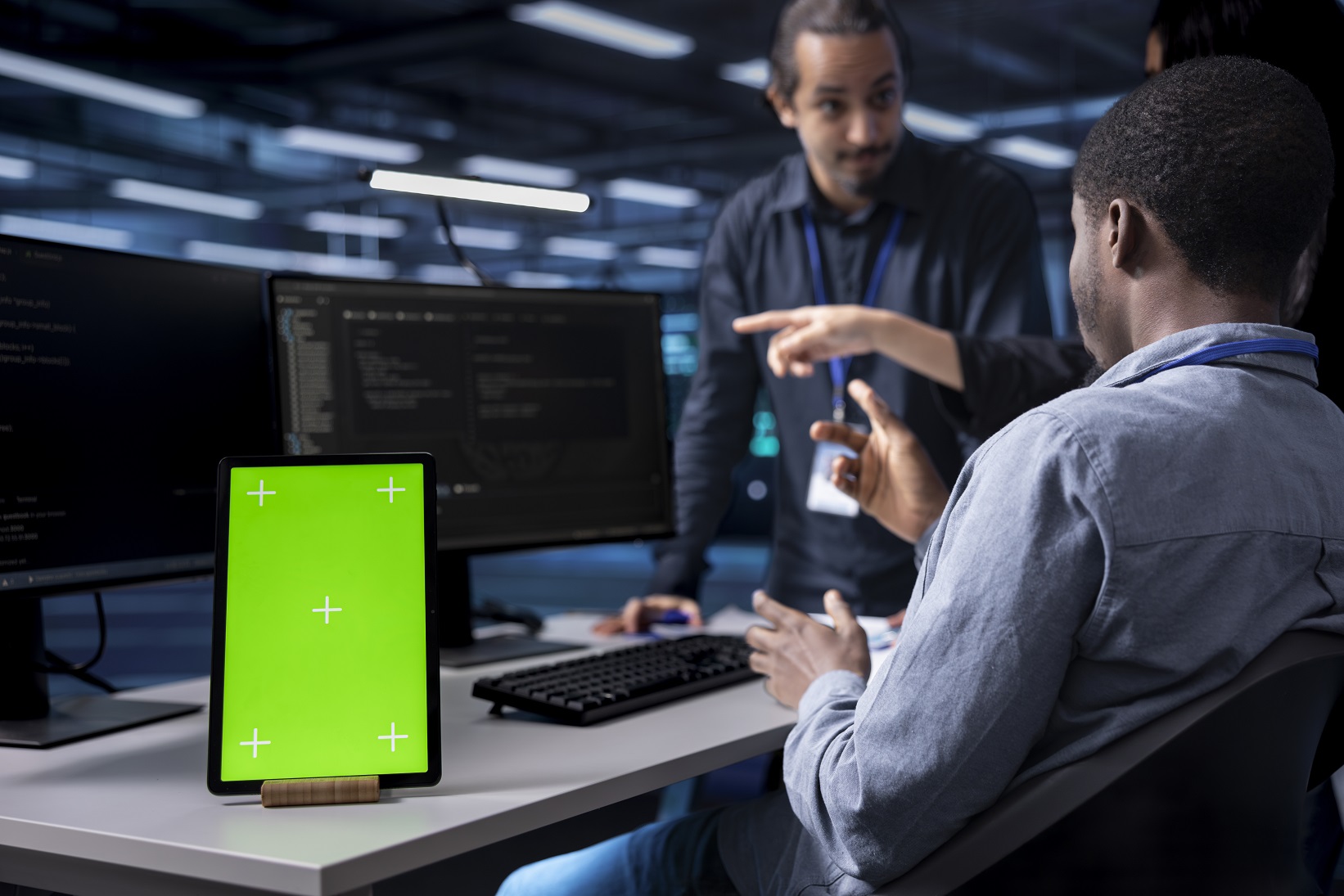 Multiethnic team using green screen tablet to oversee servers used for managing databases. Diverse staff members collaborating while working on mockup device in data center storing information